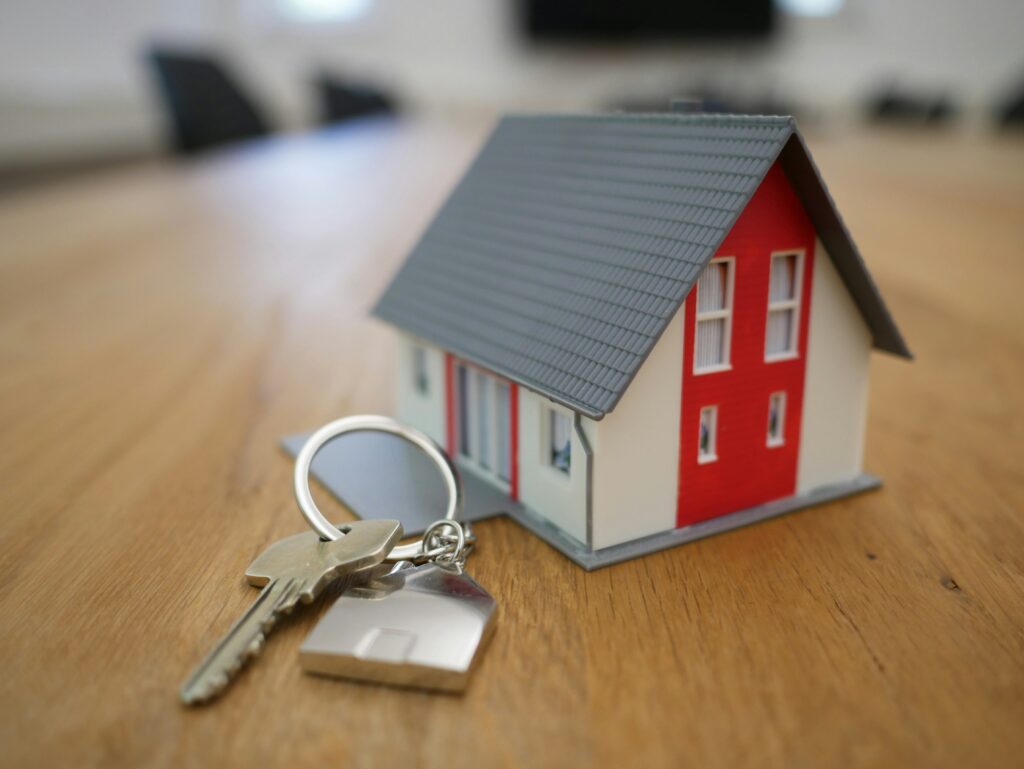 A small replica of a home next to a set of house keys.